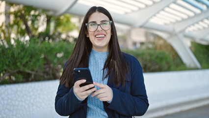 Fototapeta premium Young hispanic woman smiling confident using smartphone at park