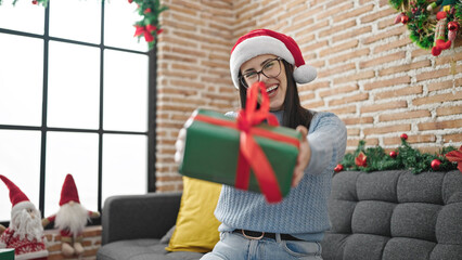 Obraz premium Young hispanic woman offering christmas gift at home