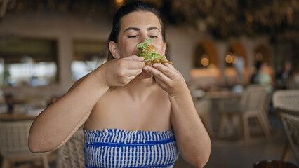 Young hispanic woman eating fusion food at the restaurant