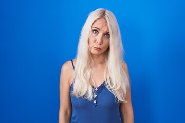 Caucasian woman standing over blue background depressed and worry for distress, crying angry and...