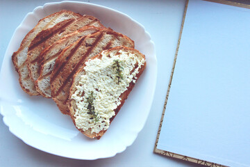 sandwiches from a loaf and with cheese paste on a wooden stand and in a white plate