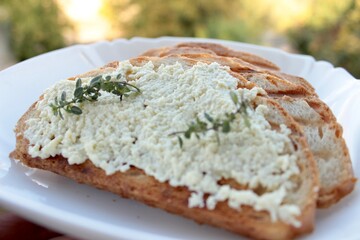 slice of bread, sandwiches from a loaf and with cheese paste on a wooden stand and in a white plate