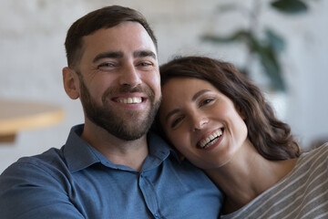 Happy attractive adult couple in love indoor head shot close up portrait. Cheerful husband and wife hugging with love, affection at home, looking at camera, smiling, laughing - obrazy, fototapety, plakaty