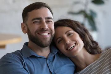 Foto op Canvas Happy attractive adult couple in love indoor head shot close up portrait. Cheerful husband and wife hugging with love, affection at home, looking at camera, smiling, laughing © fizkes