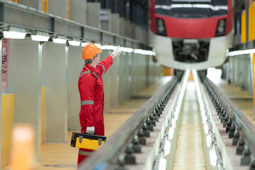 Electric vehicle engineer with toolbox inspect the machinery of the electric train according to the inspection round. After the electric train was parked in the electric train's repair shop
