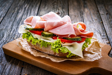 Sandwich with mortadella pistachios, tapenade and cheese on wooden table
