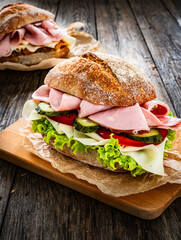 Sandwich with mortadella pistachios, tapenade and cheese on wooden table
