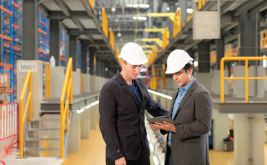 Two businessmen inspect the electric train system using a tablet to reserve equipment for use in repairing tracks and machinery of the electric train transportation system.