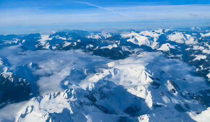 Fototapeta na wymiar Aerial view of Alps mountain range with snow and blue sky.