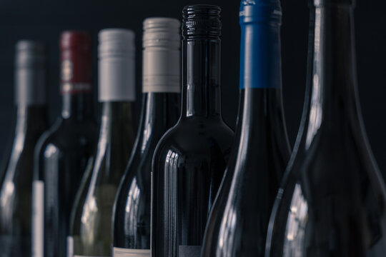 Close up of set of wine bottles standing on dark background with narrow focus