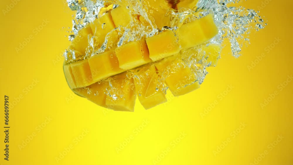 Poster super slow motion of falling mango fruit. splashing into water on colored background. filmed on high