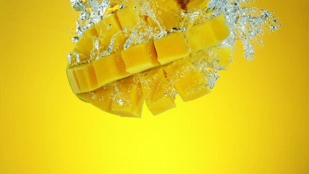 Super Slow Motion of Falling Mango Fruit. Splashing Into Water on Colored Background. Filmed on High Speed Cinema Camera, 1000 fps.
