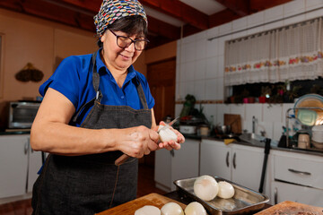 Low angle view of unrecognizable latin woman chopping onion with a knife, for filling homemade...