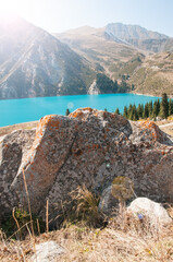 Big Almaty Lake in the Republic of Kazakhstan with its turquoise water and huge boulder in the foreground