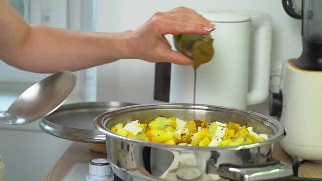 A woman adds soy sauce and stirs the cooking dish of zucchini and feta cheese. Close-up. Diet dish.