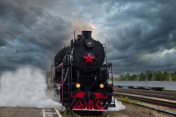 An old steam locomotive of the early 20th century on the railway track.