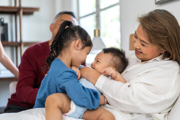 Portrait of happy love asian grandmother playing with asian baby and little cute girl on bed.Big family love with their laughing grandparents smiling together.Family and togetherness