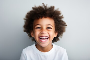 A professional portrait studio photograph featuring an adorable, mixed-race young boy with immaculately clean teeth, radiating joy with laughter and smiles. This image is isolated on white background - obrazy, fototapety, plakaty