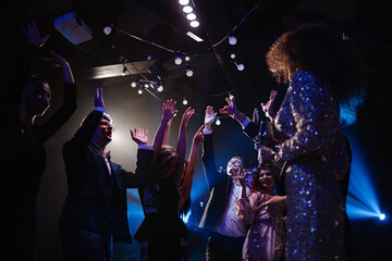 happy group of friends celebrating new years eve party dancing throwing confetti enjoying glamorous...