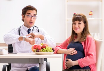 Pregnant woman visiting doctor discussing healthy diet