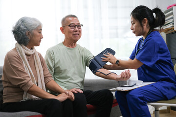 Attentive doctor or healthcare worker giving professional advice to senior couple during home visit