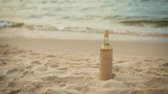 Bottle of white wine in retro style by sea at sunset. Preparation for beach party