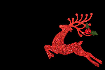 Christmas Eve reindeer sparkling red tree ornament on black with holly. Festive symbol santa helper...