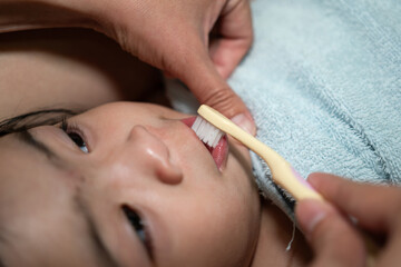 Action of a mother is using toothbrush to cleaning teeth for a baby. Close-up and selective focus, photo contained some noised.