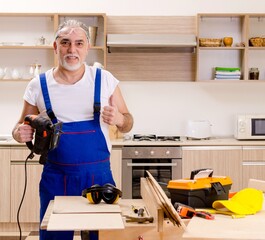 Aged contractor repairman working in the kitchen