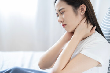 Young Asian lazy woman got neck ache after waking up in morning, woman feel pain at neck after woken up.