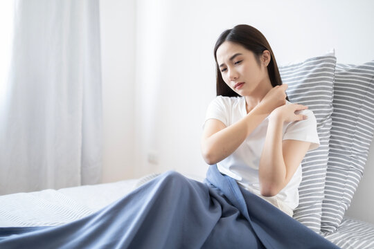 Young Asian lazy woman got shoulder ache after waking up in morning, woman feel pain at shoulder after woken up.