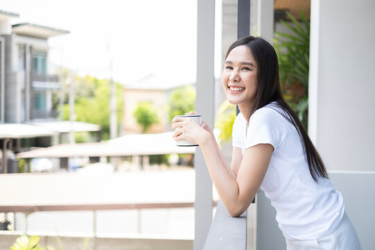 Young Asian beautiful woman drinking coffee and looking away with snile of happiness inthe moring, fresness moment for starting in morning.