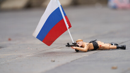Toy crawling warrior with Russian flag in hand on gray surface. Copy space.