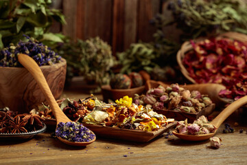 Various dried medicinal plants, herbs, and flowers on an old wooden background.