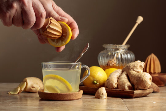 Ginger tea with lemon and honey on a brown ceramic table.