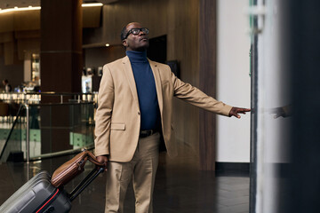 African American man with luggage pushing the button and waiting for the elevator © AnnaStills