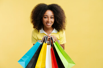 Portrait smiling beautiful African American woman holding colorful shopping bags looking at camera - obrazy, fototapety, plakaty