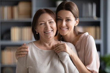 Head shot different generation relatives women standing in living room looking at camera, adult...