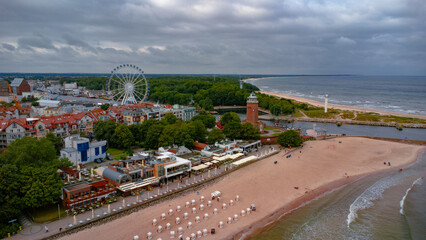 Kolobrzeg town before the rain. Ferris wheel, lighthouse, harbour and sandy beach. Taken from a drone. Kołobrzeg is a city in Poland. - obrazy, fototapety, plakaty