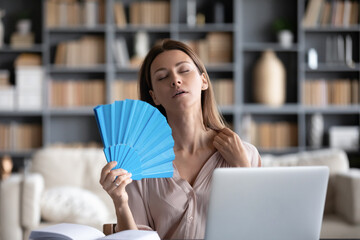 Woman sweating suffering from heat stroke, high temperature at home sitting at table in cozy living...