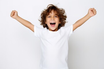 Mockup T-Shirt  - Kind freut sich und reißt die Arme hoch. Weißer Hintergrund und weißes T-Shirt mit fröhlichem Kleinkind im Studio.  - obrazy, fototapety, plakaty