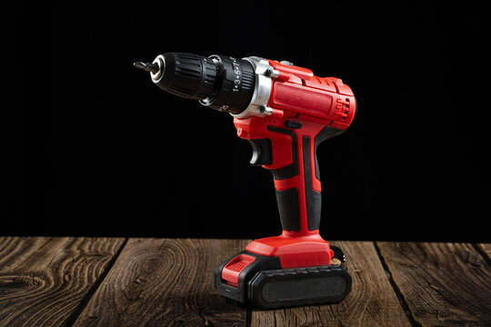 The cordless screwdriver is red on a dark background.