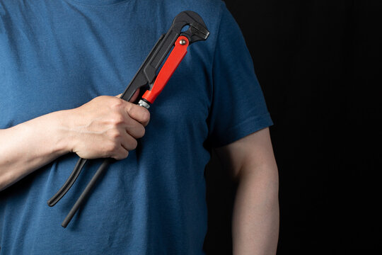 A plumber with a tool for installing and repairing plumbing on a black background.