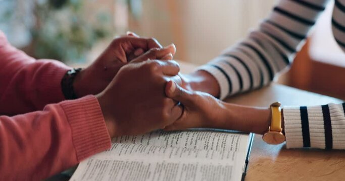 Closeup, holding hands and bible for faith in religion, worship and prayer in home. Man, woman and married couple with care, support and trust in God for spiritual wellness as christian at table