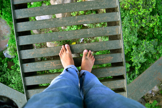 First person view of bare foot at metal bridge at adventure location