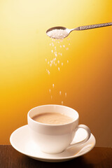 Sugar teaspoon pouring into cup