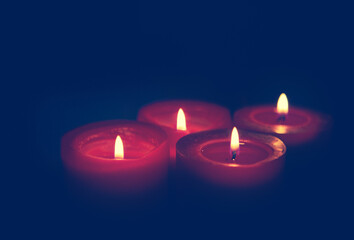 Four burning red Advent candles on black background. - Powered by Adobe