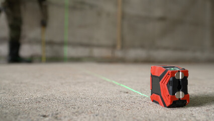 A laser level marks out lines for markings on a construction site. A builder takes measurements...