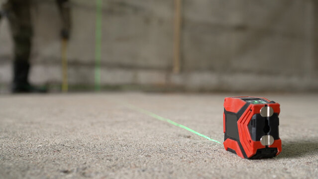 A laser level marks out lines for markings on a construction site. A builder takes measurements using a laser level at a construction site. Laser level at a construction site.