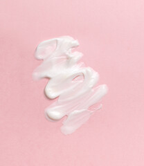 Body care cream smeared on a pink background.